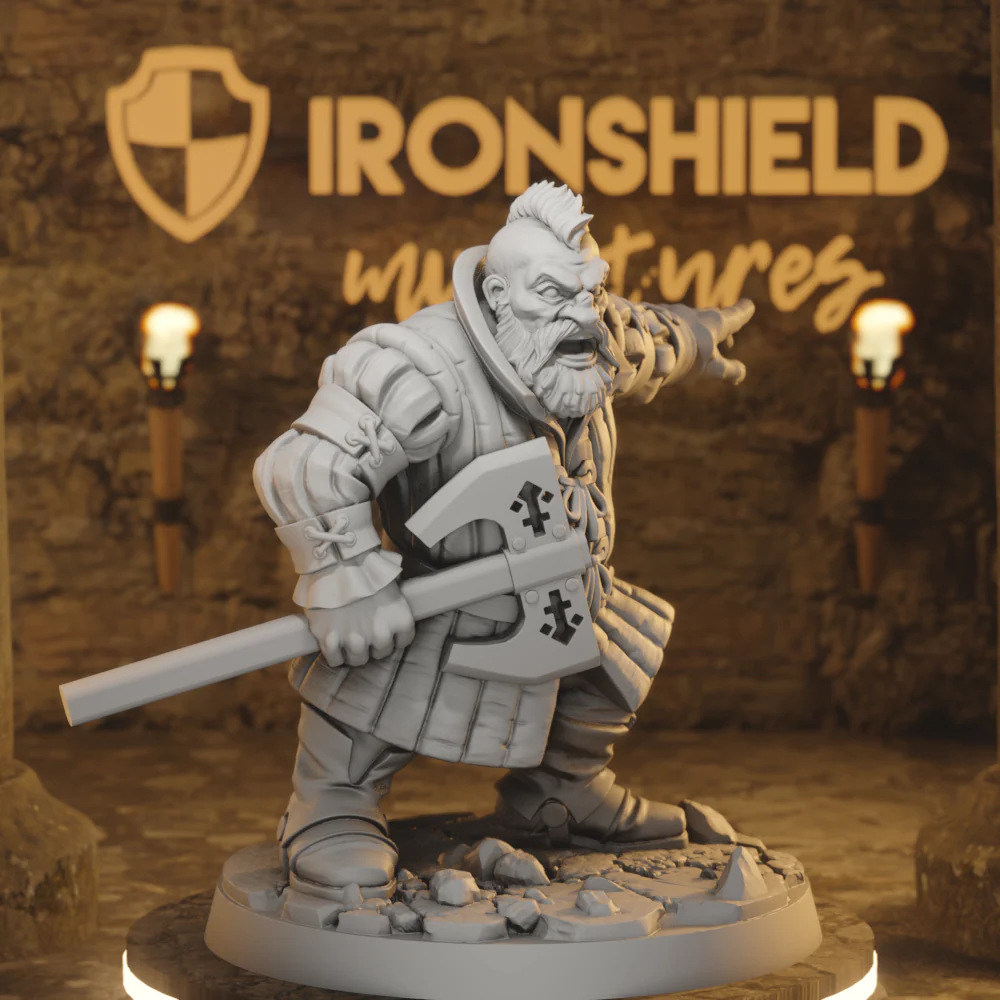 Fantasy dwarf warrior miniature in armor, gripping a large doubled-edged axe, standing on a rocky base in a studio with Ironshield Minis signage in the background.