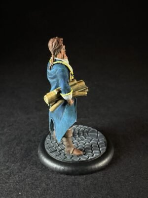 IMG_1461 Miniature figure in a blue coat holding rolled scrolls, standing on a cobblestone base, facing left against a dark background.