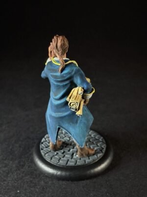 IMG_1462 Back view of a miniature figure in a blue cloak holding rolled parchments, standing on a cobblestone base.
