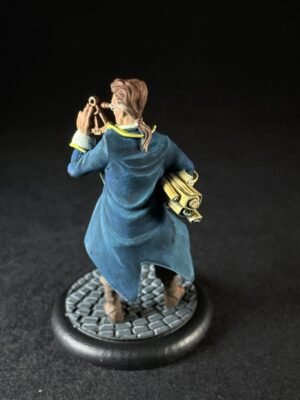 IMG_1463 Miniature explorer in a blue coat holds a telescope to his eye, with rolled maps tucked under his arm, standing on a cobblestone base.