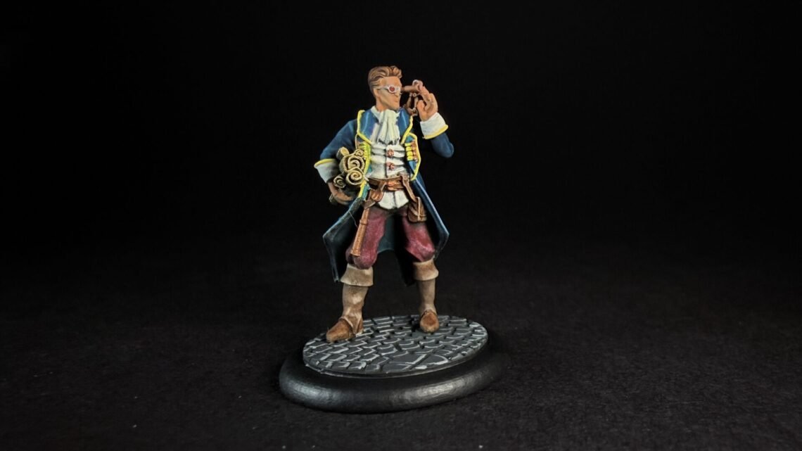 Miniature pirate captain in a blue coat with yellow trim, holding a telescope to his eye, standing on a textured circular base.
