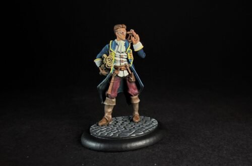 Miniature pirate captain in a blue coat with yellow trim, holding a telescope to his eye, standing on a textured circular base.