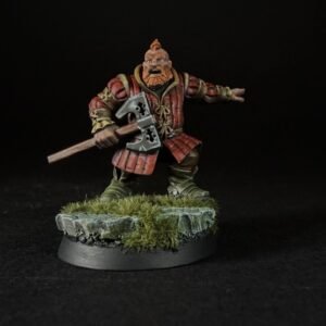 Miniature dwarf warrior in red armor wielding a double-headed axe on a rocky grassy base, black background.