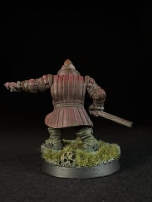 IMG_1495 Back view of a red-brown armored knight miniature with a raised left arm and sword, standing on a grassy base with a skull on dark background