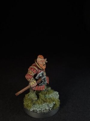 IMG_1500 Miniature dwarf warrior with orange beard in red armor, holding a battle axe, standing on a mossy, rocky base.