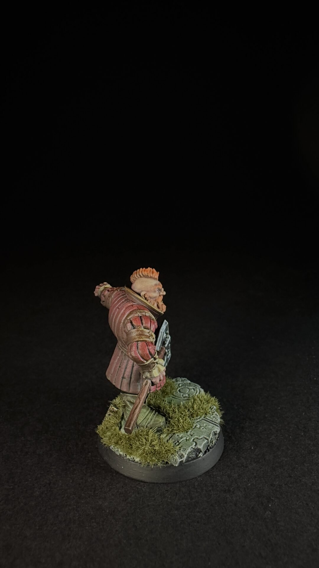Tabletop miniature of a red-armored knight, holding a weapon, standing on a grassy, mossy base.