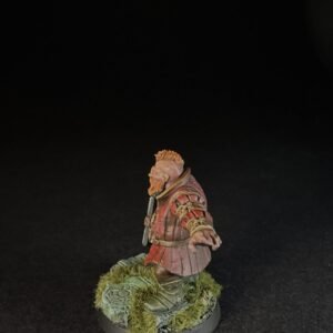 Miniature bearded warrior in red armor standing on a mossy base against a black background.