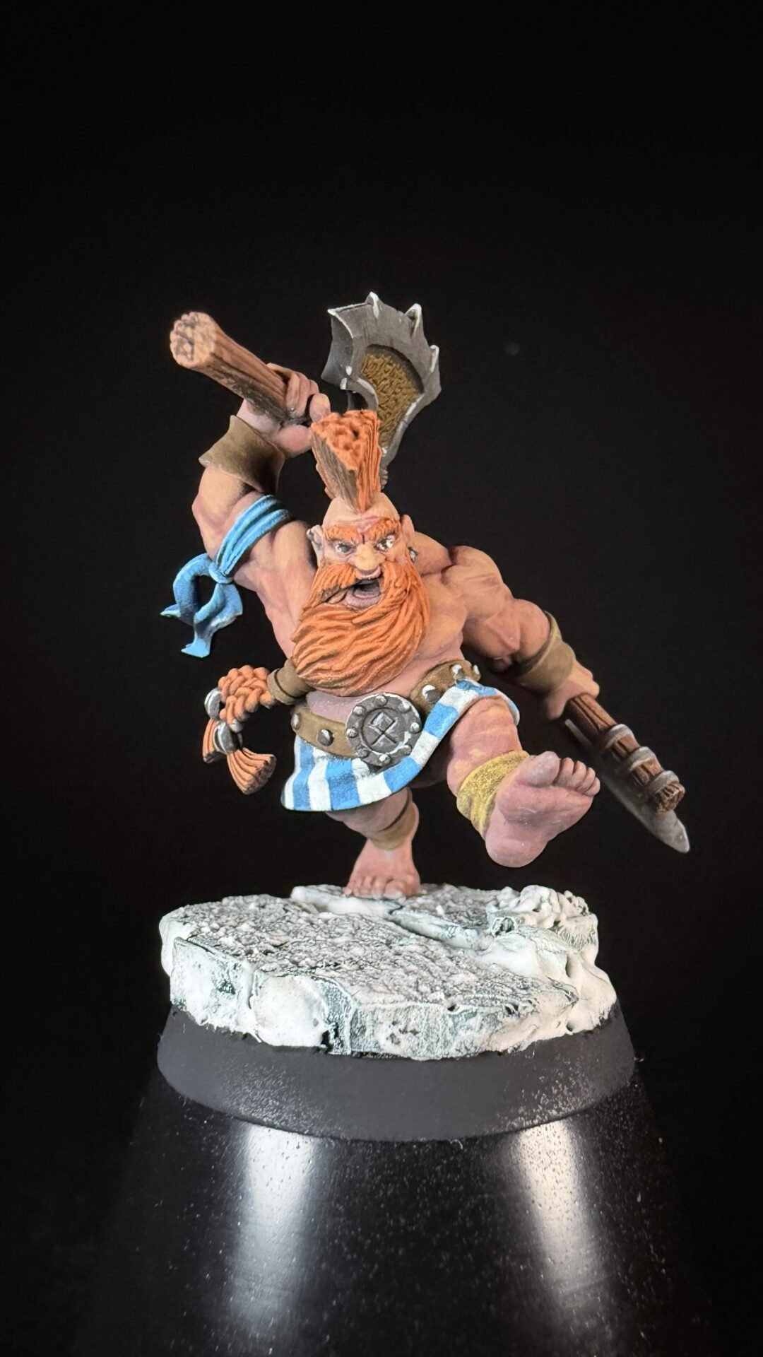 Miniature dwarf warrior with orange beard swinging a large battle axe on a snowy rocky base.