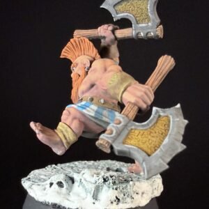 Miniature fantasy warrior with two axes, orange beard, bare chest, blue-striped loincloth, standing on a rocky base.