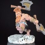 Tabletop fantasy dwarf miniature in a leaping battle pose, wielding a large axe over his shoulder and a hammer in his other hand, standing on a rocky snowy base.