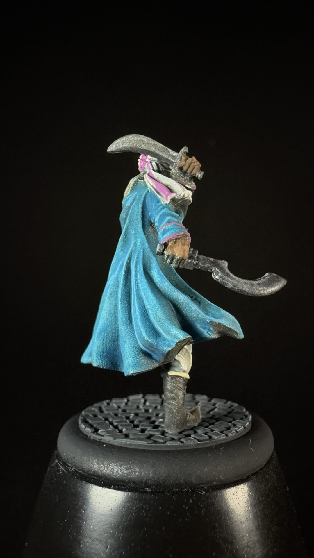 Fantasy swordsman miniature in a blue cloak, wielding a curved silver blade on a round base.
