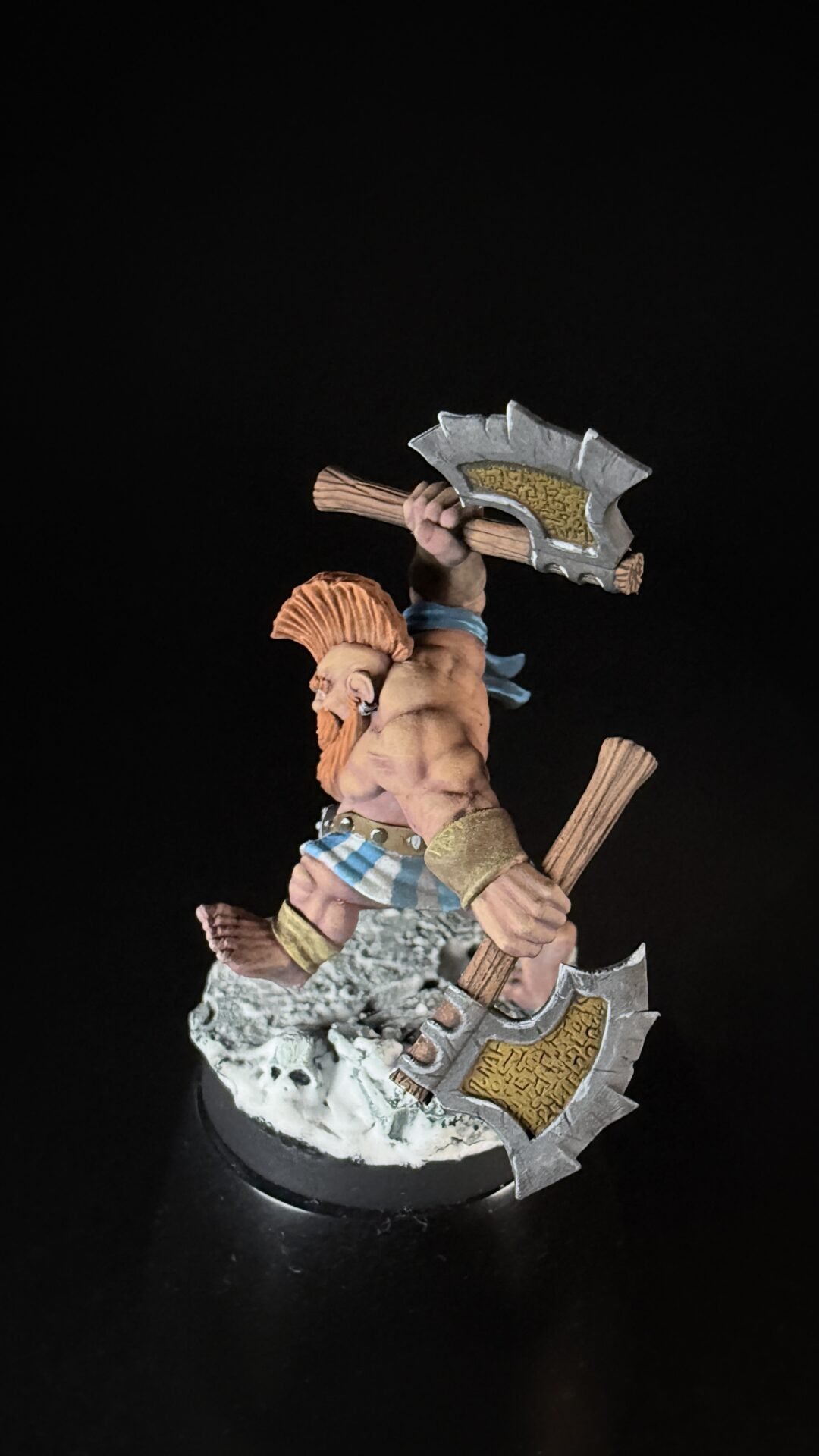 Painted miniature of a muscular Viking with orange hair raising a double-headed axe on a rocky base.