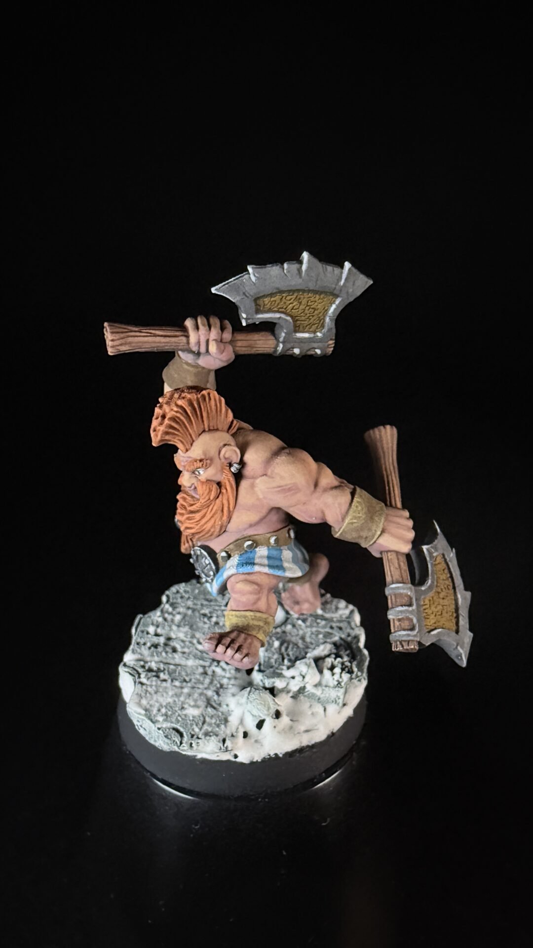 Fantasy barbarian warrior with orange hair, wielding a large double-headed axe above his head, standing on a rocky base.