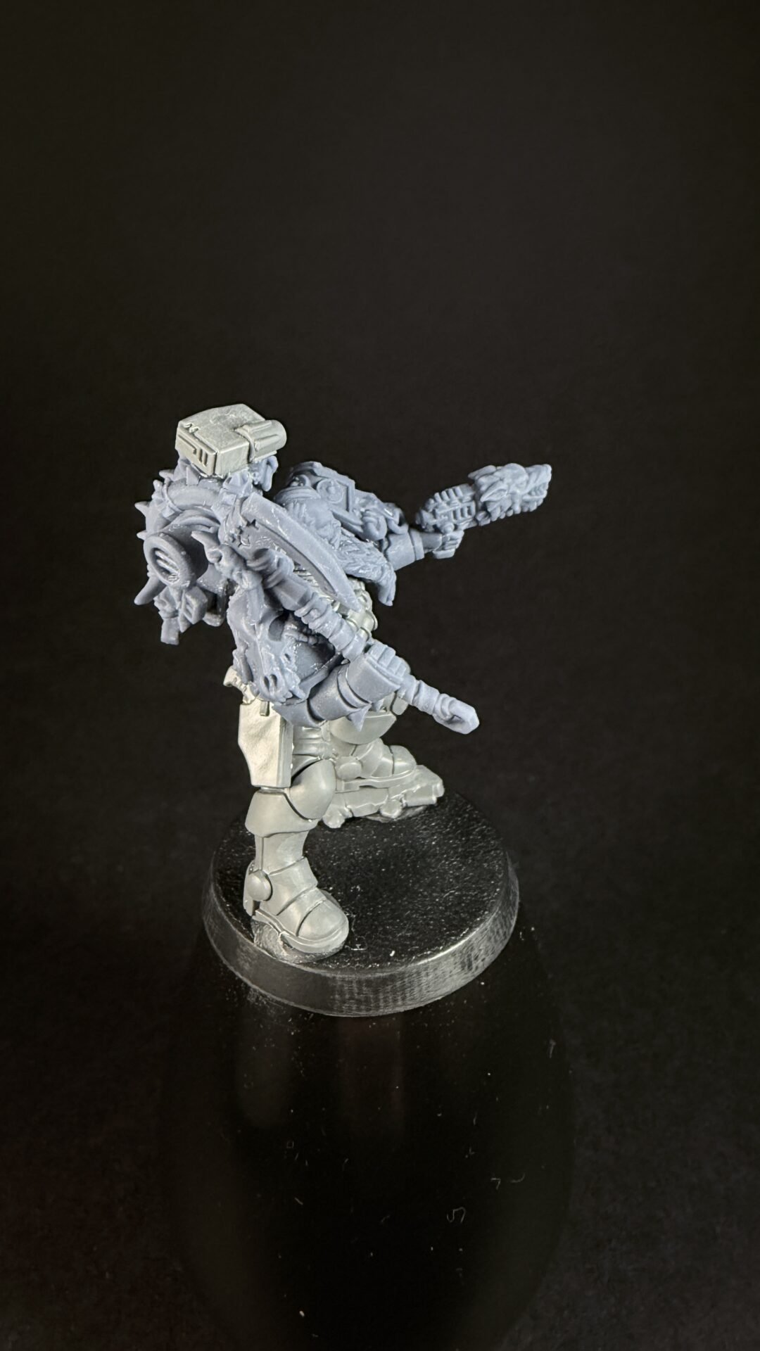 Grey plastic tabletop miniature: heavily armored warrior with a large chained weapon, standing on a round black base.