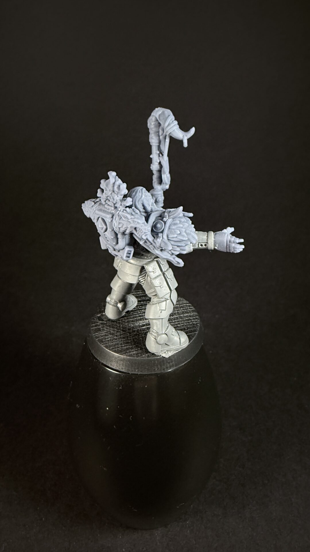 Plastic mini figure of a heavily armored warrior, raising a tall, ornate weapon on a textured round base.