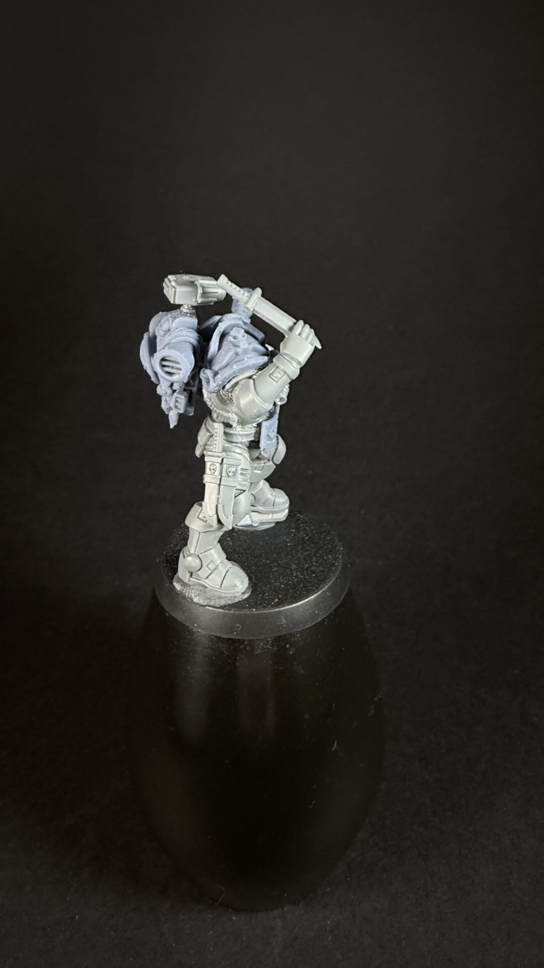 Gray sci-fi power-armored miniature raising a large hammer above its head on a round base.