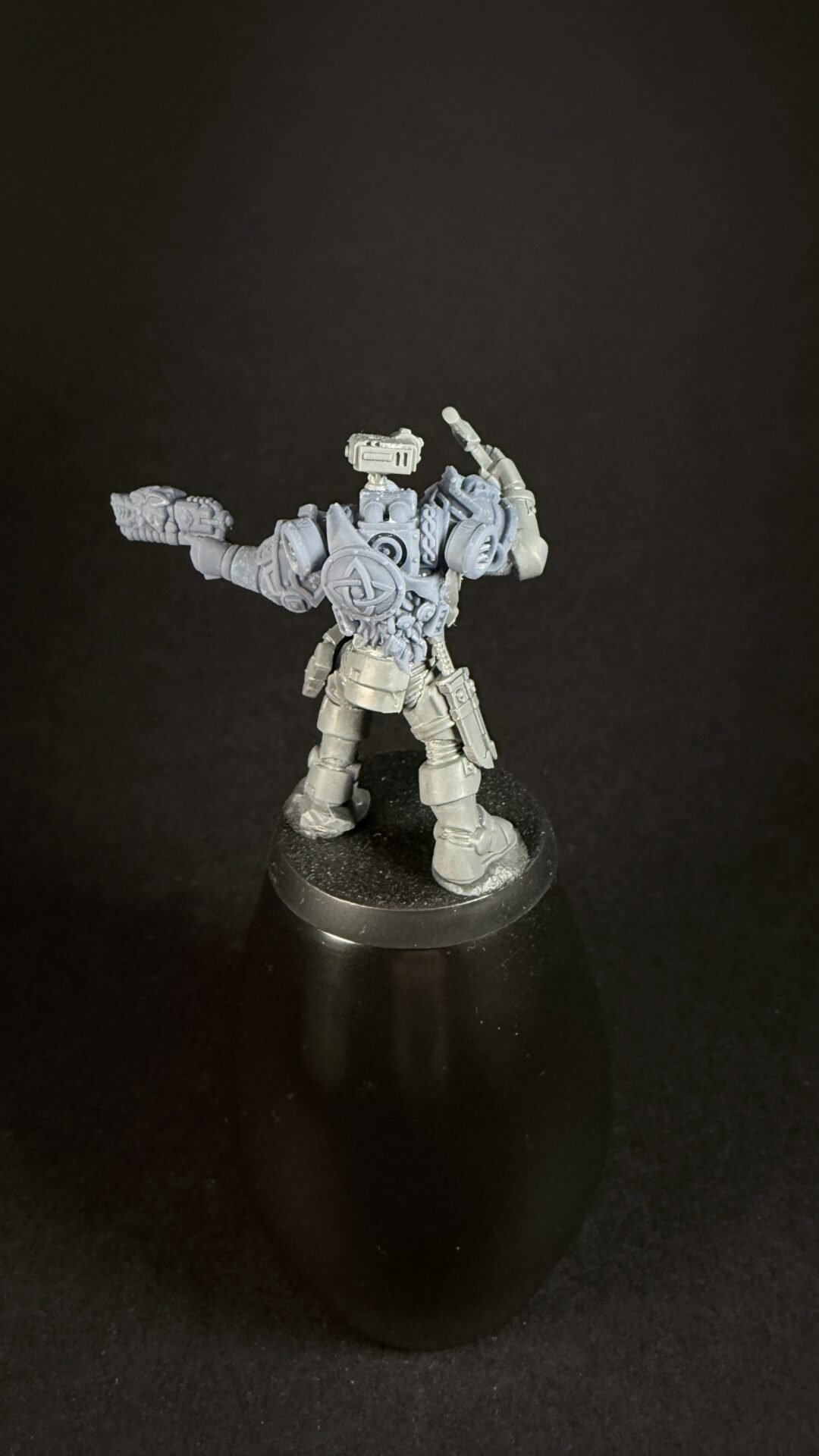 Grey plastic space marine miniature on a round base, armed with a bolter in one hand and the other arm raised in a dynamic pose.