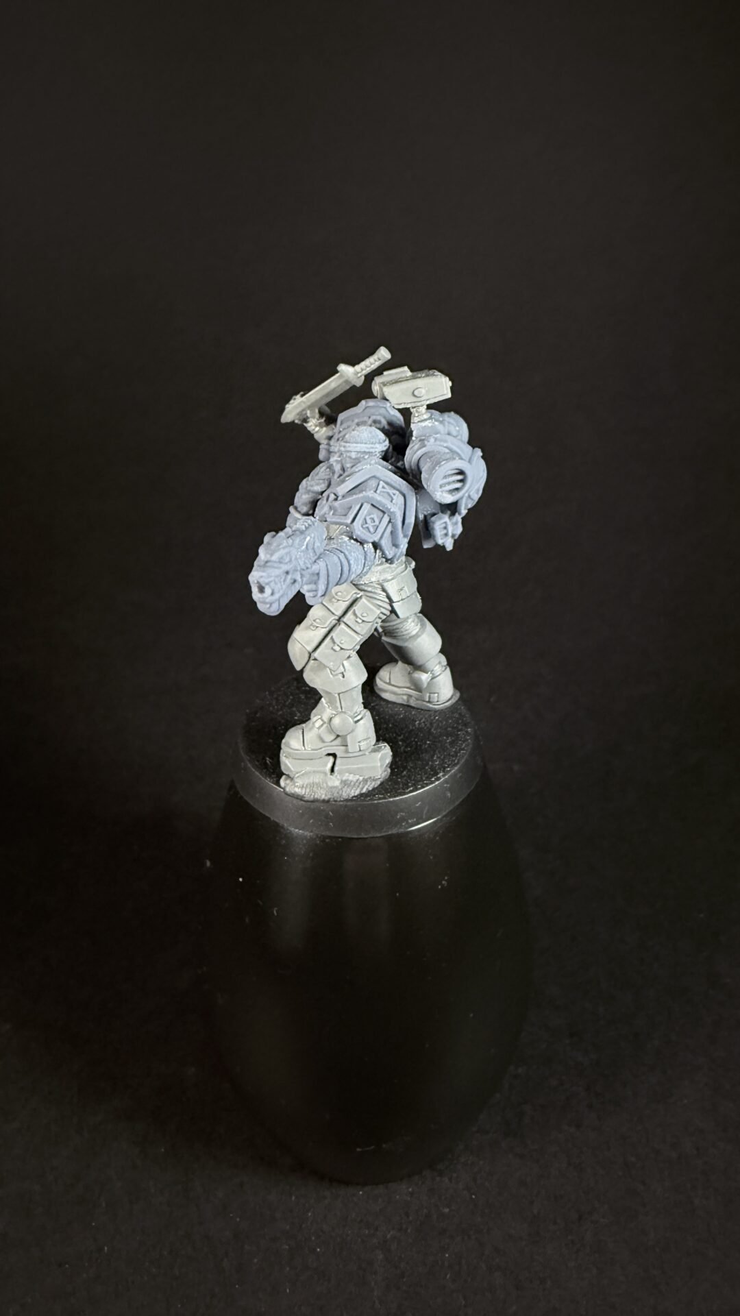 Armored sci-fi trooper miniature posed on a round base, holding a handheld weapon and backpack equipment, set against a dark background.