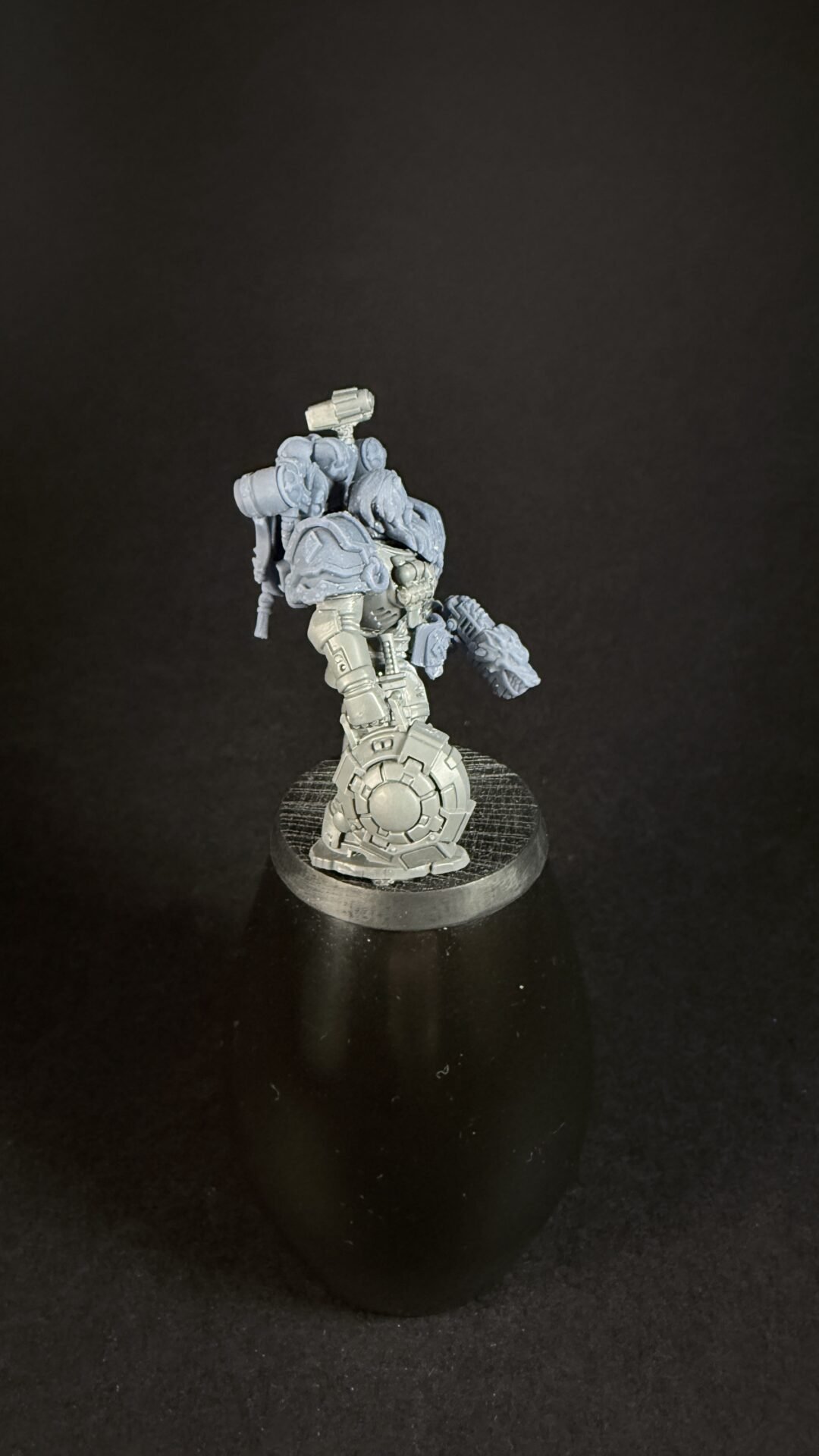 Unpainted grey plastic sci‑fi armored mech miniature on a round textured base.