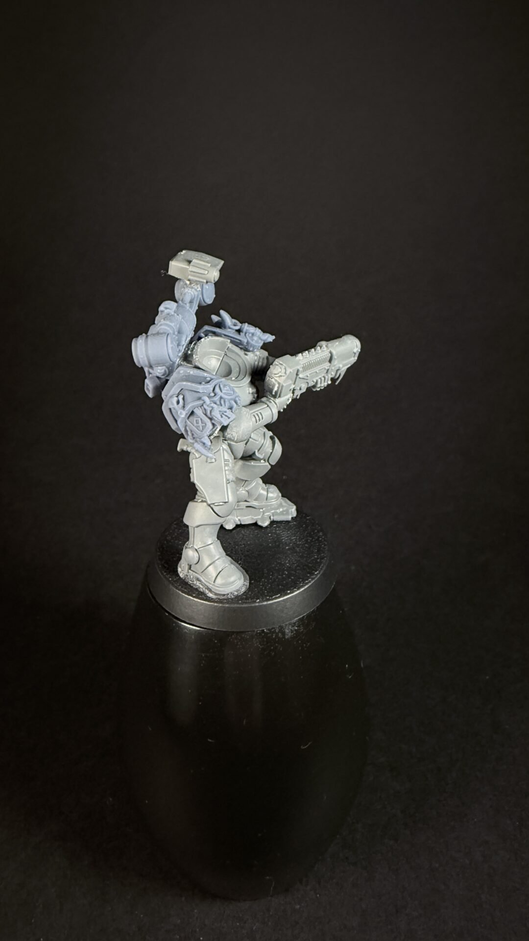 Gray plastic sci‑fi armored miniature with a large rifle, posed on a black base on a pedestal stand.