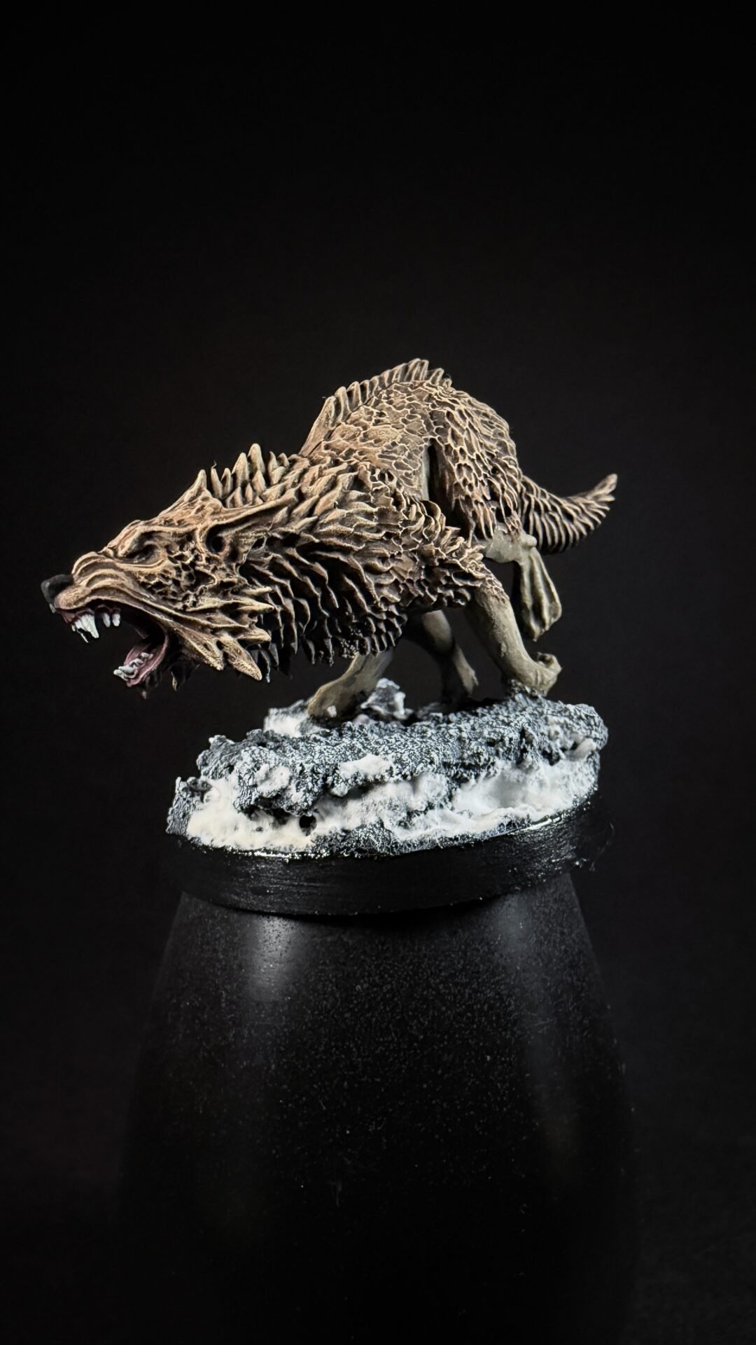 A detailed model of a spiky, bone-textured dragon-like creature snarling on a snowy rock pedestal against a black background.
