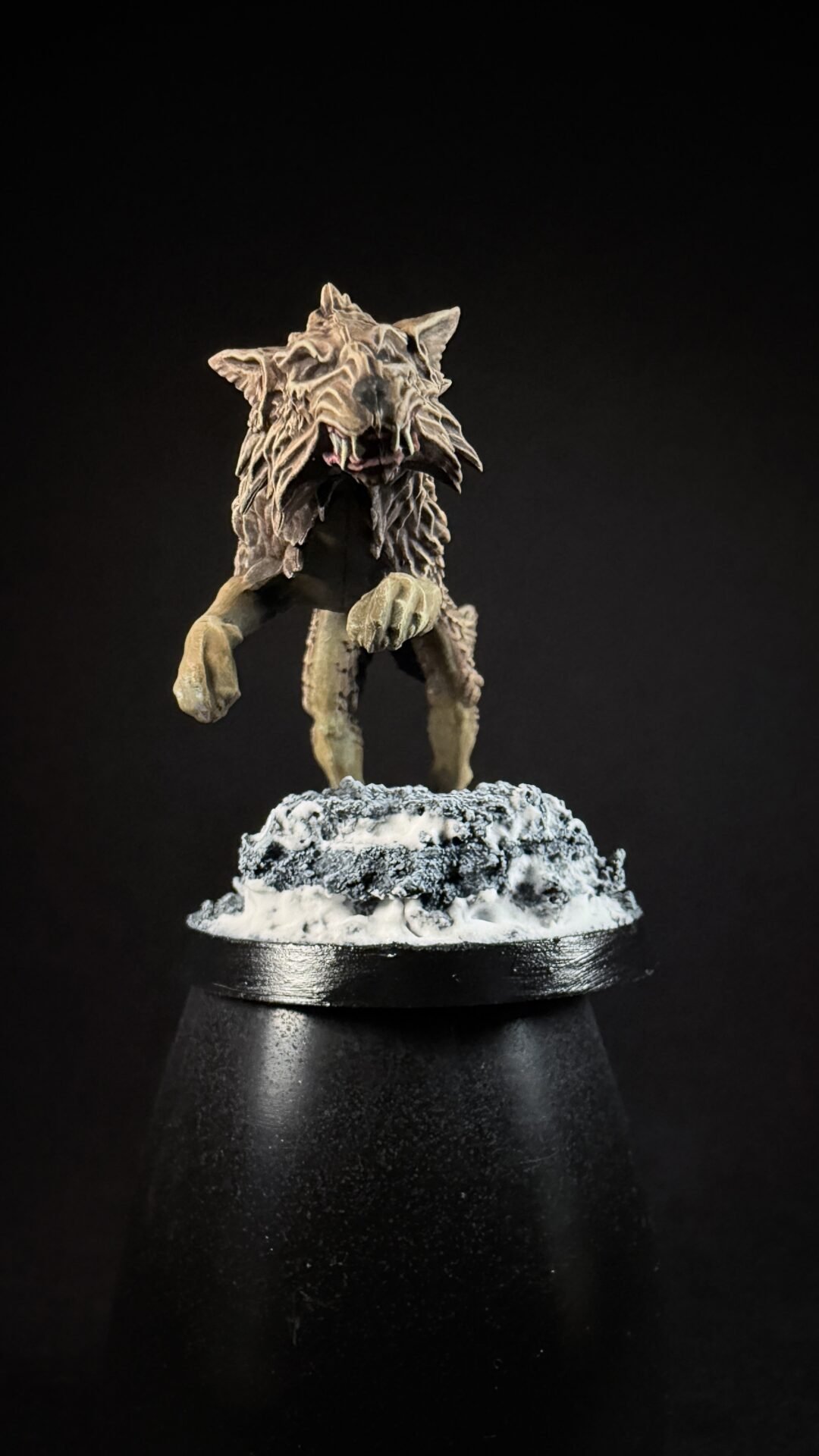 Miniature of a snarling, furred monster standing on a snow‑covered rocky base against a black background.