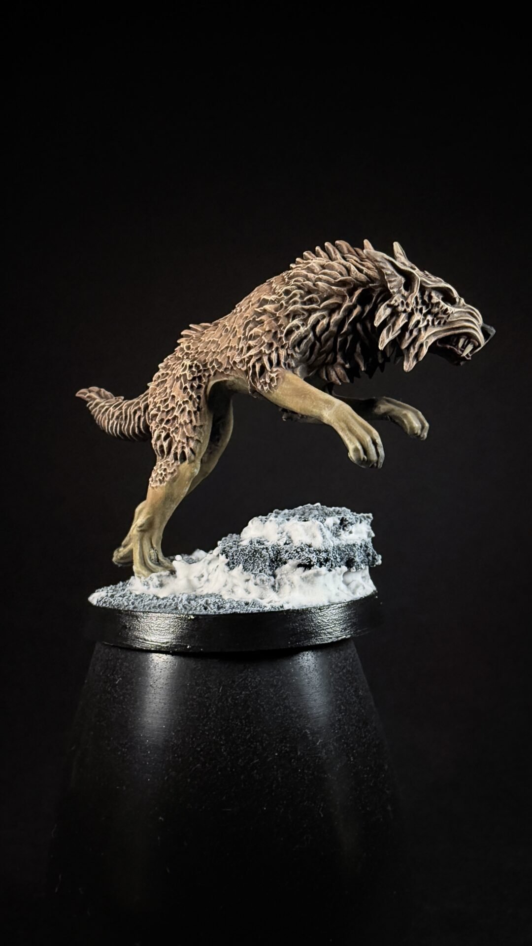 Fantasy wolf-like creature sculpture mid-pounce on a snowy rocky base, set against a black backdrop.