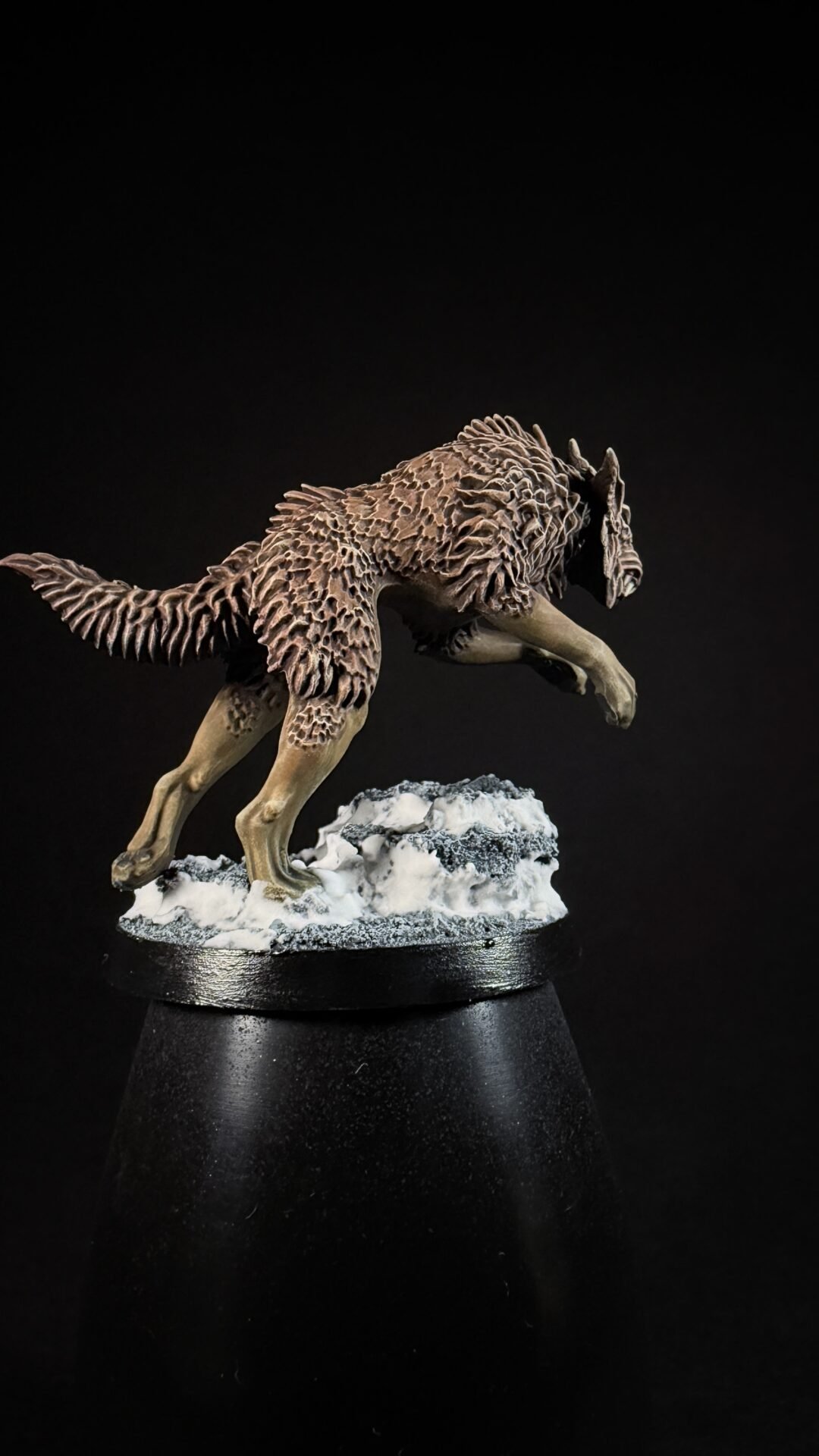 Detailed dinosaur sculpture with spiky, ridged skin leaping over snow on a black pedestal.