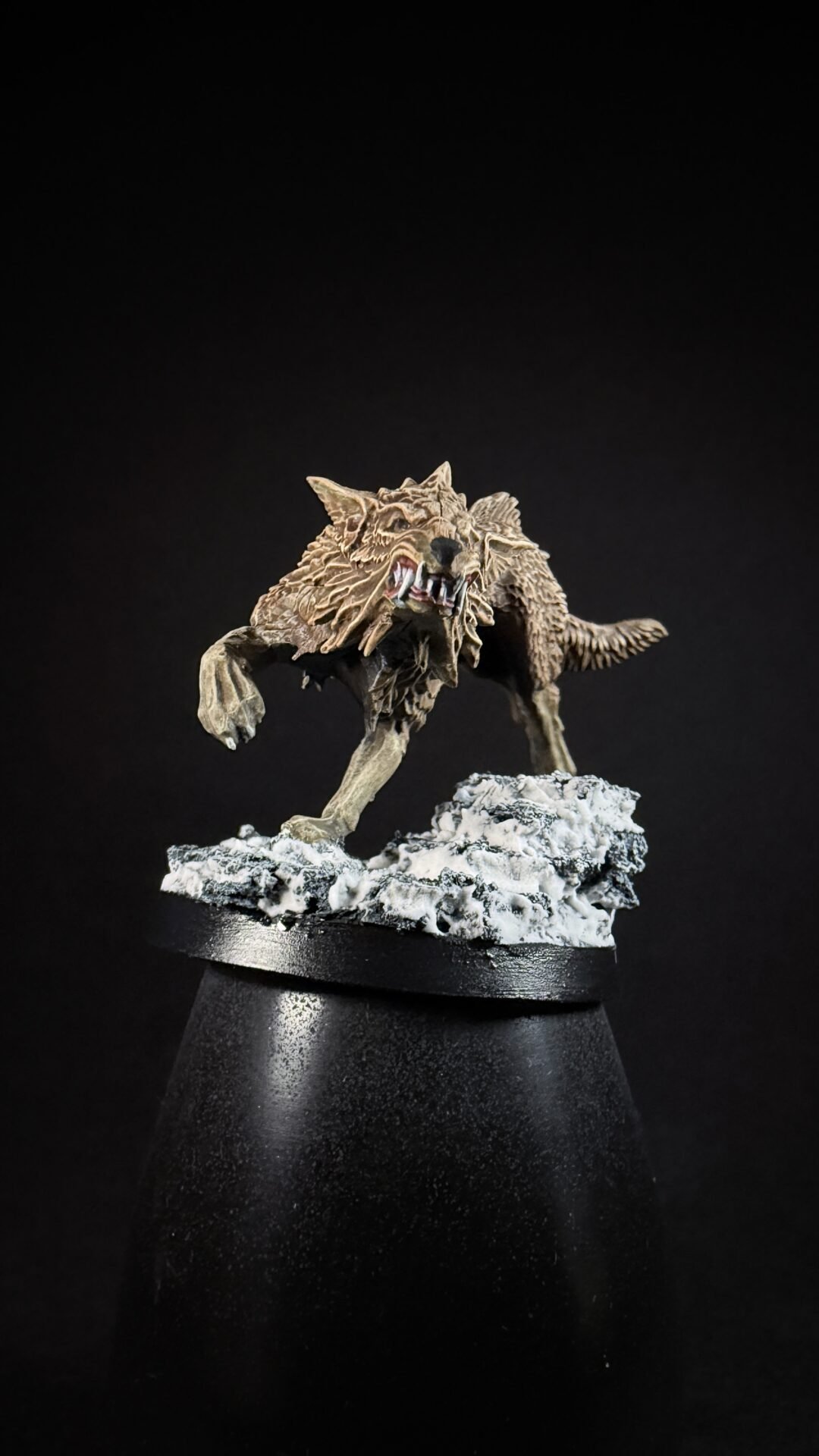 Detailed werewolf miniature snarling on a snow-covered rock base, posed mid-step on a display stand.