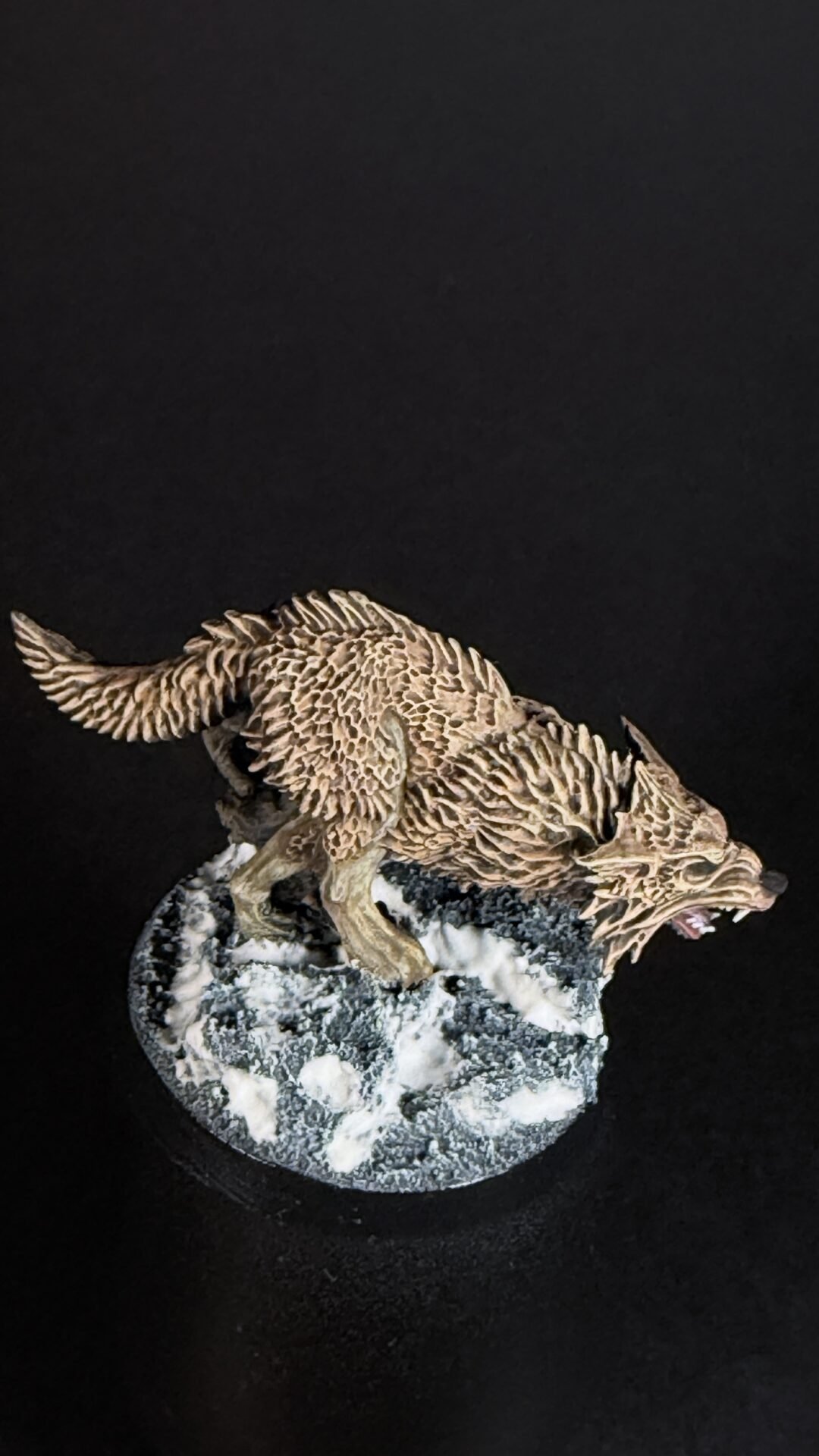 Sculpted wolf figure crouching on a snow-dusted rock, snarling at the edge of the base.