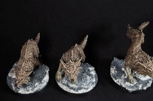 Three fenrisian wolves miniatures standing on rocky, snow-covered