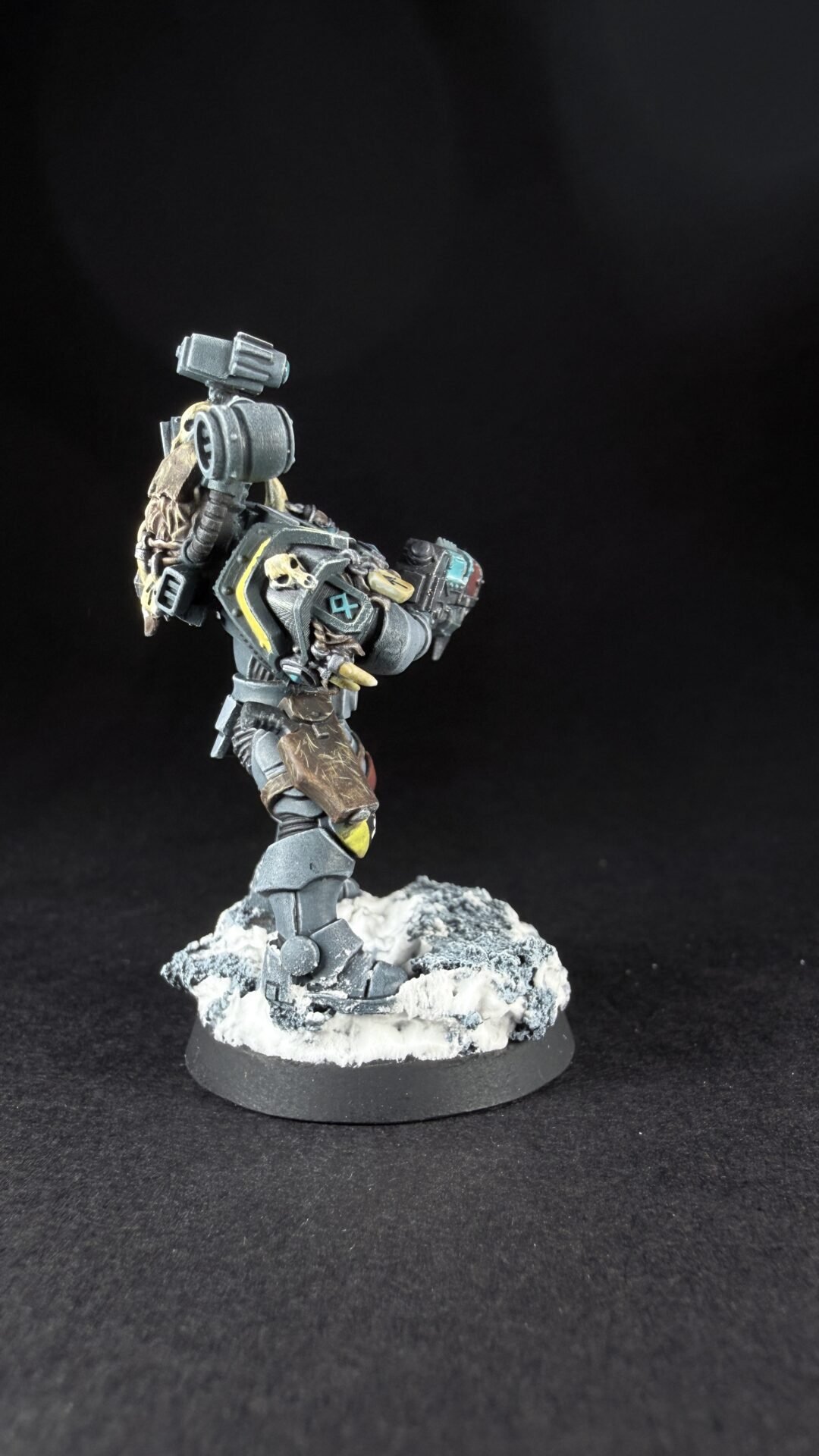Armored sci-fi miniature on a snowy rocky base, holding a large cannon-like weapon over its shoulder.