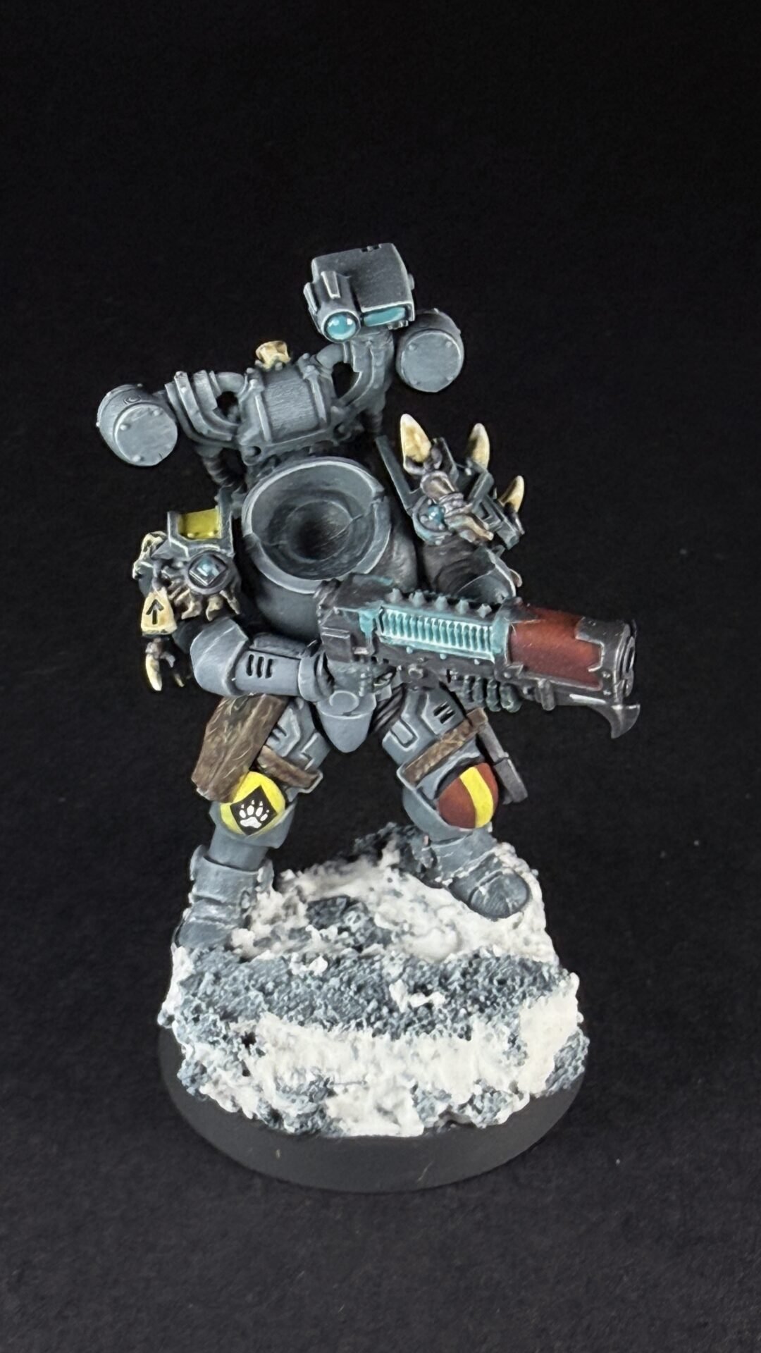 Armored sci-fi battle droid standing on a snowy base, wielding a large gun with teal accents and yellow markings.