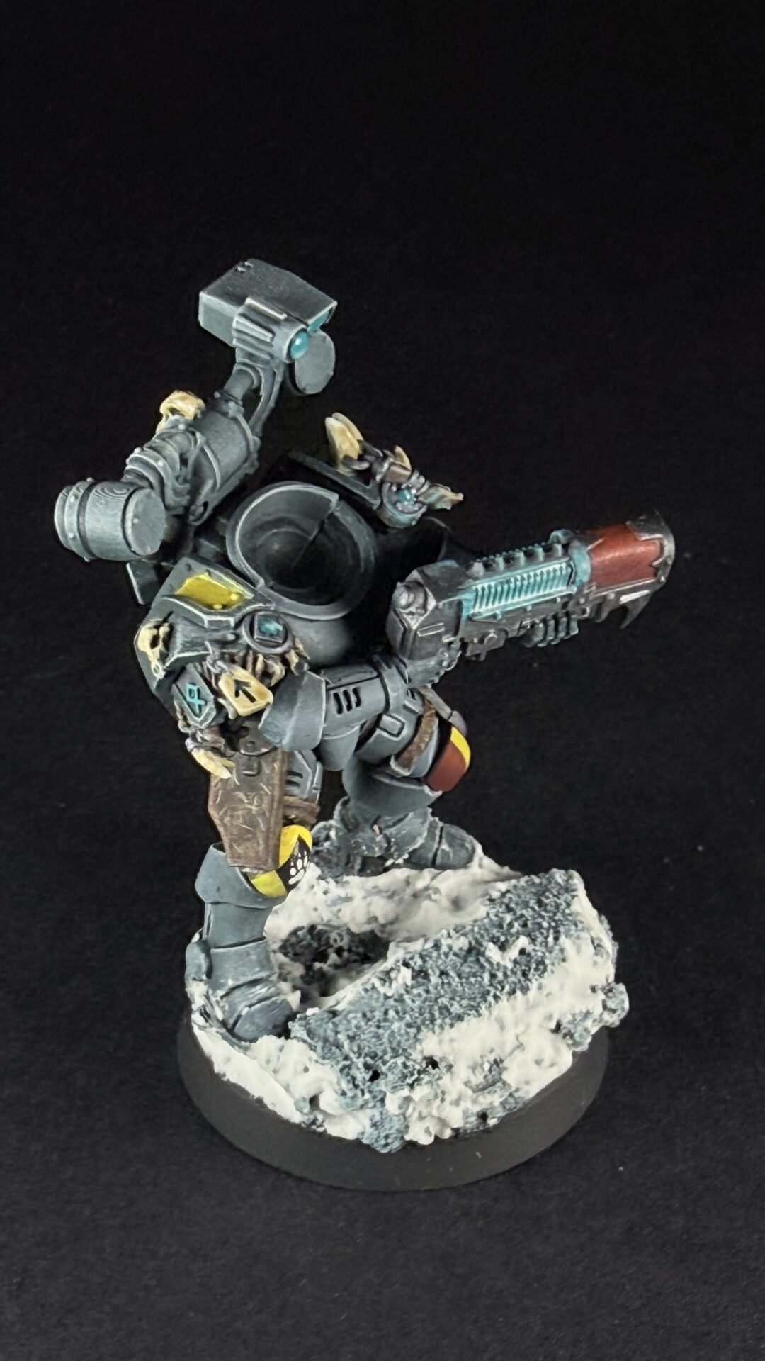 Painted sci-fi miniature of a heavily armored figure firing a large gun, standing on a snowy rocky base.