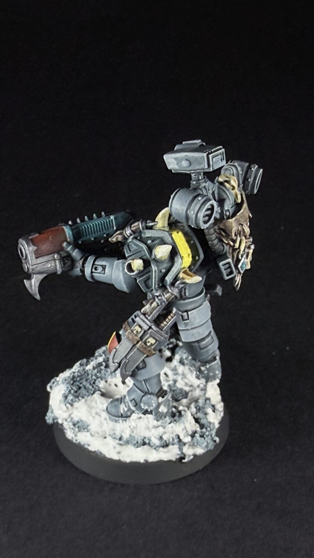 Sci-fi armored miniature figure holding a large weapon, standing on a rocky snowy base against a black background.