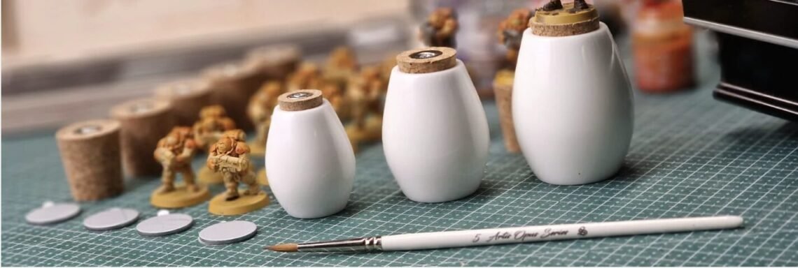 Miniature painting workspace with small toy soldiers, cork stoppers, and a brush on a green cutting mat.