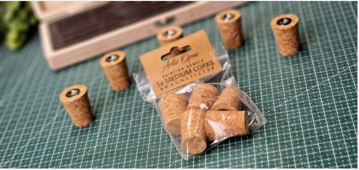Bag of small wine corks labeled 'Medium Corks' on a green cutting mat, with loose corks nearby for crafts or DIY projects.